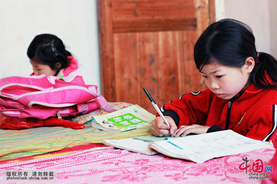 孙雪女的两个孙女放学后在租房里写作业，床沿就是他们的完成作业的桌子。中国网图片库 曾勇摄