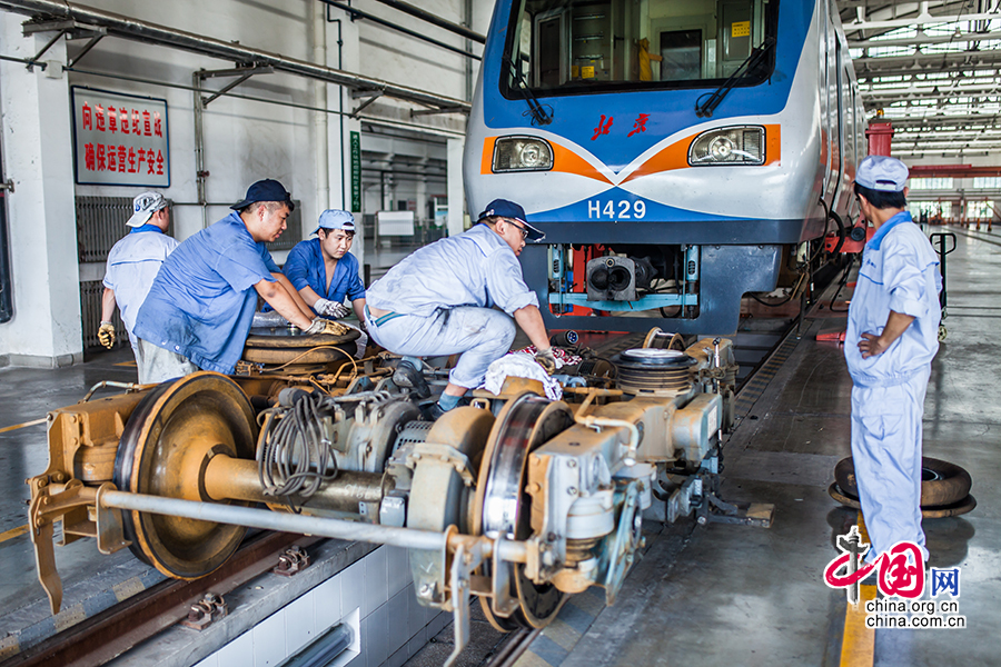 正在工厂内对地铁车辆进行检修的工人,这里的维修工人采用分班制保证