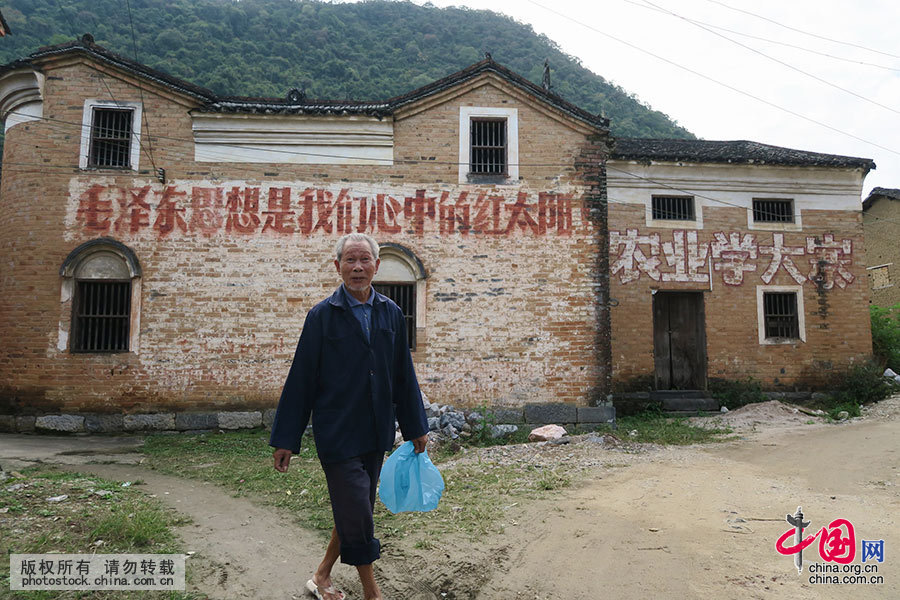 11月7日，在广西桂林市恭城瑶族自治县莲花镇东寨村，村民从一条标语下走过。中国网图片库 王滋创 摄