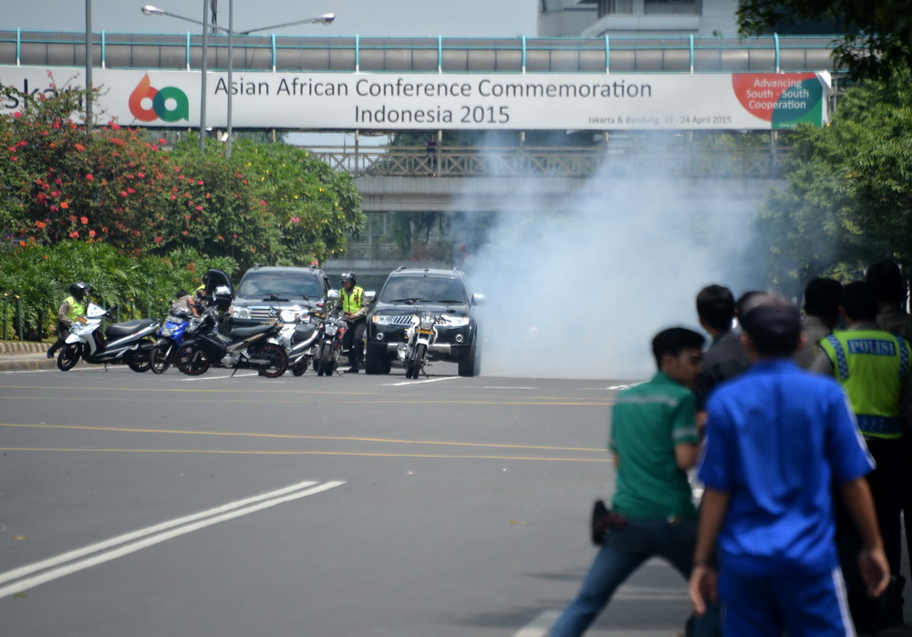 1月14日，在印度尼西亞首都雅加達，警察（左）隱蔽在車輛後與武裝分子交火。