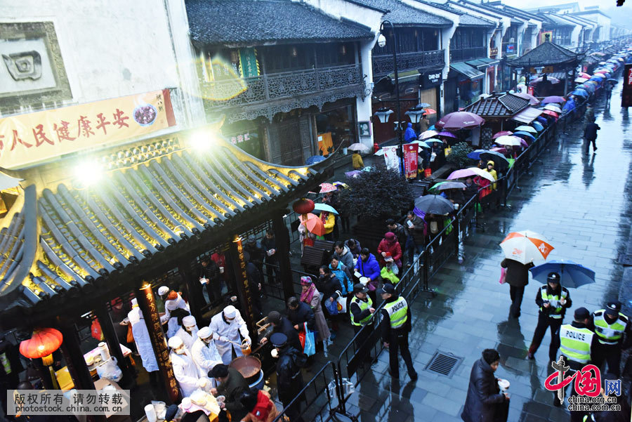 2016年1月17日，浙江省杭州市，市民在杭州河坊街上冒雨排队领腊八粥，上万市民的长长队伍形成了“长龙”。中国网图片库 龙巍摄