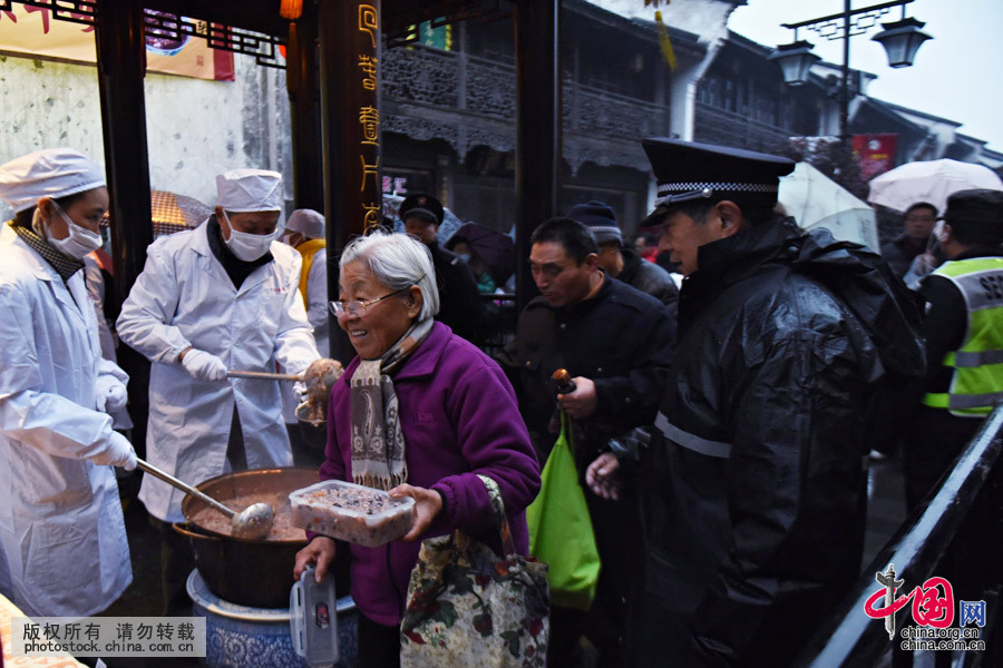 2016年1月17日，浙江省杭州市，市民在杭州河坊街上冒雨排队领腊八粥。中国网图片库 龙巍摄