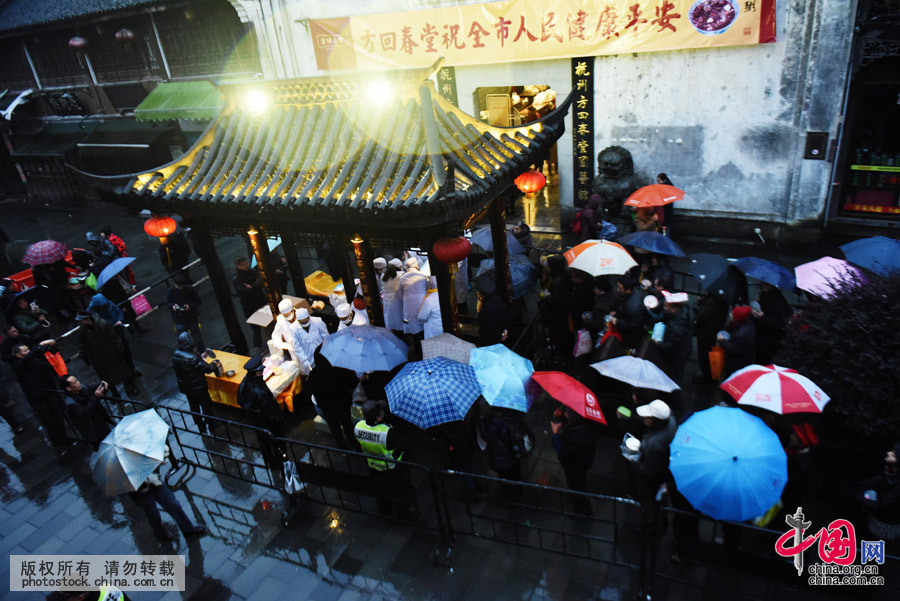 2016年1月17日，浙江省杭州市，市民在杭州河坊街上冒雨排隊領臘八粥。中國網圖片庫 龍巍攝