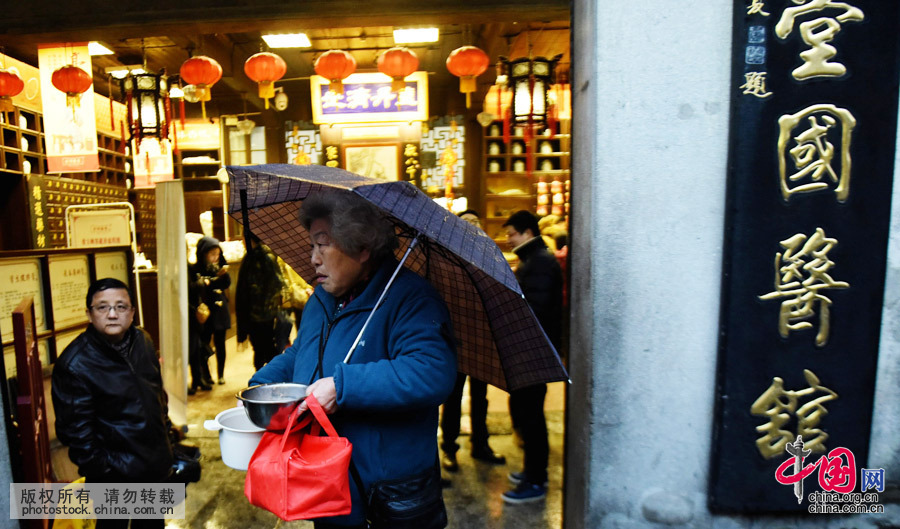 2016年1月17日，浙江省杭州市，市民在杭州河坊街上冒雨排队领腊八粥。中国网图片库 龙巍摄