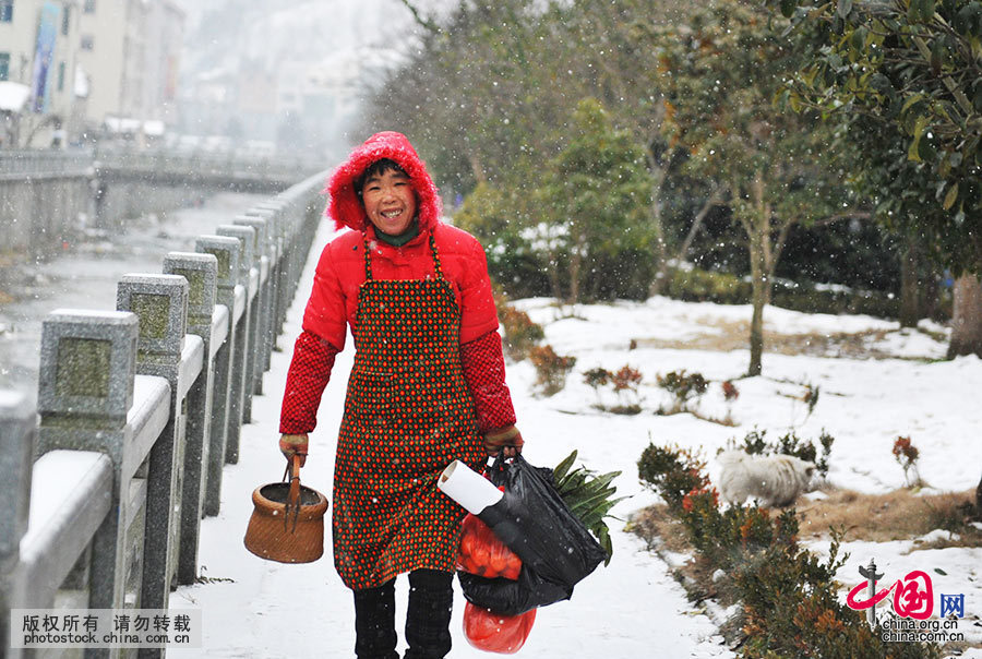 在浙江省临安市昌北农村，进入冬季，走街串巷也少不了拎着一个火熜取暖，一名村民在大雪纷飞的日子里手拎火熜买菜。中国网图片库 胡剑欢 摄
