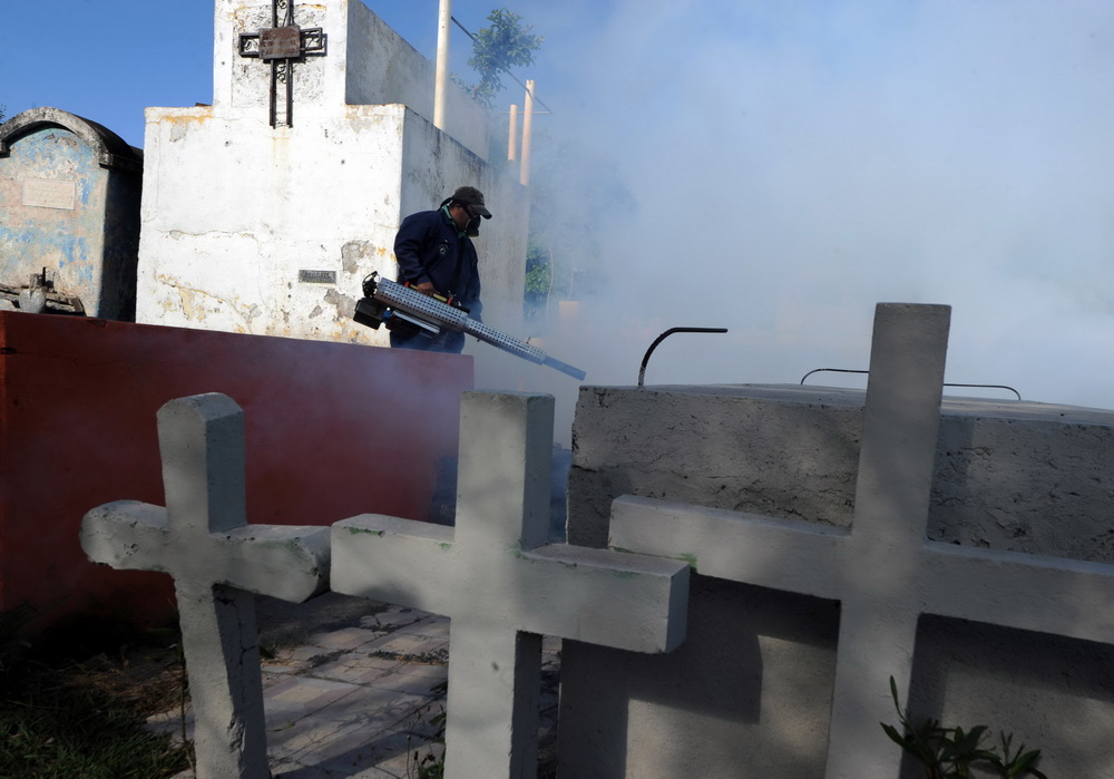 这是1月21日，在洪都拉斯首都特古西加尔巴，一名卫生部工作人员在一处公墓喷洒灭蚊药剂。