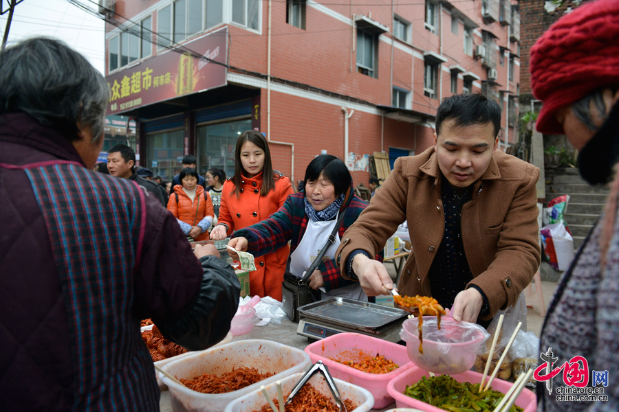 2016年1月26日，陳位齊夫妻與媽媽在出售自製腌菜。當日是何市鎮上趕集的日子。