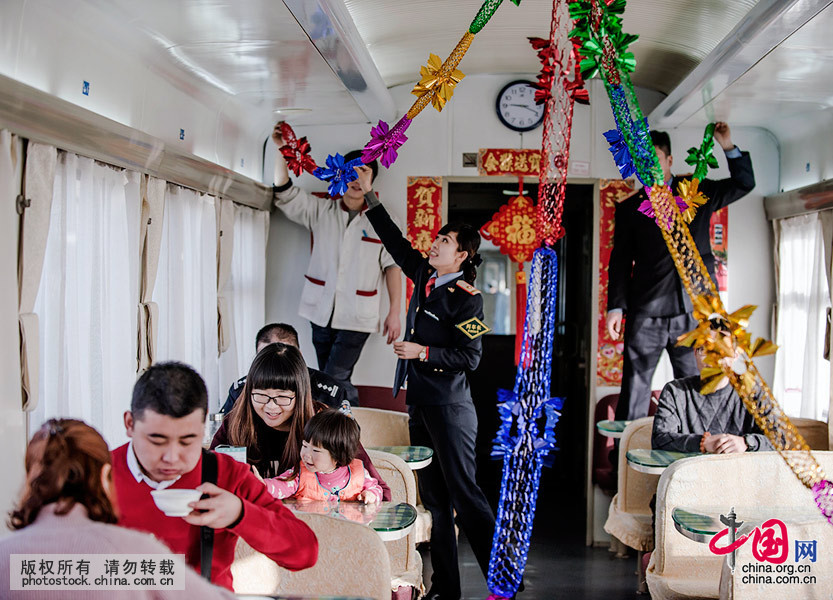  2月7日除夕早晨8点，列车长刘莉莉带领司乘人员开始贴窗花，粘春联，挂中国结。旅客欢声笑语，整个车厢一派节日景象。中国网图片库 刘国兴摄