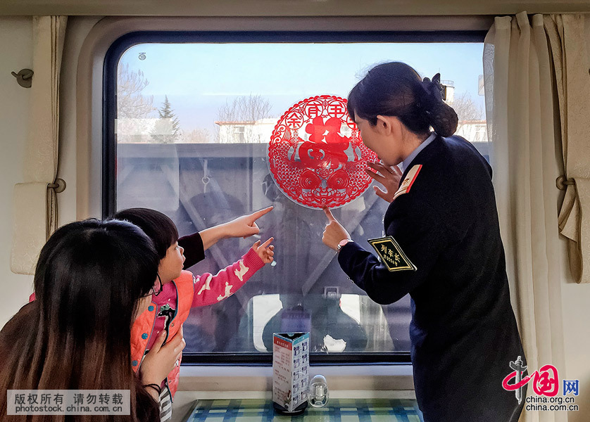  2月7日早，列车长刘莉莉和乘客一起贴窗花。中国网图片库 刘国兴摄