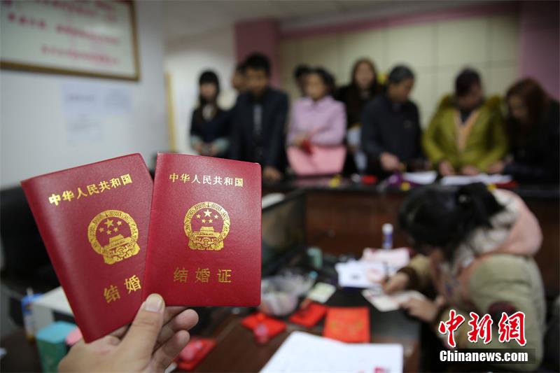 2月14日,在四川省内江市东兴区婚姻登记处,新人在展示刚领取的结婚