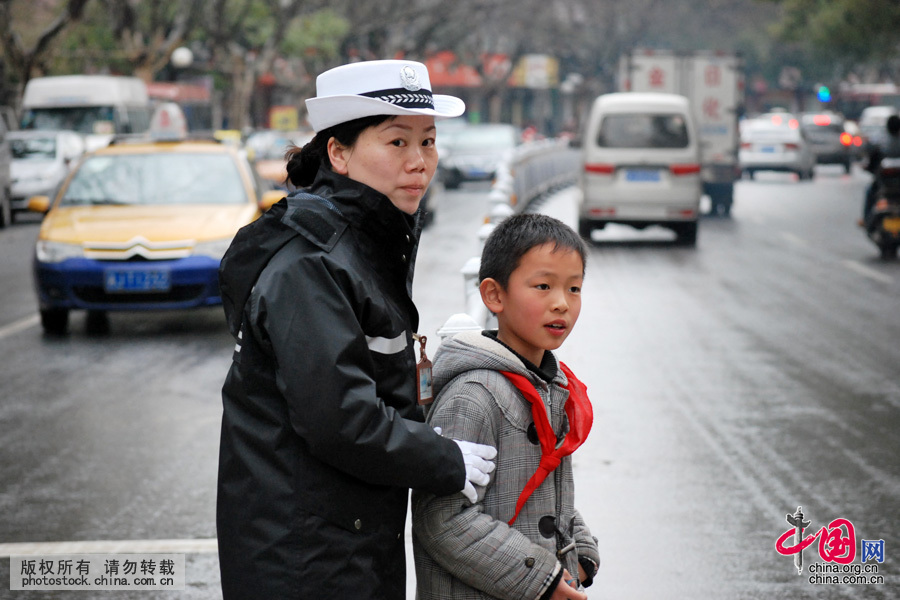 2011年3月21日，微博上把这张图片叫做“最美妈妈”。她只是护学岗中的一员，让孩子们远离危险，可以平安的上学、回家。日复一日，年复一年，那些已经长大的孩子对她说：“阿姨，您辛苦了。”在她心中，始终有一种坚守的力量，风雨无阻。中国网图片库 陈自德摄