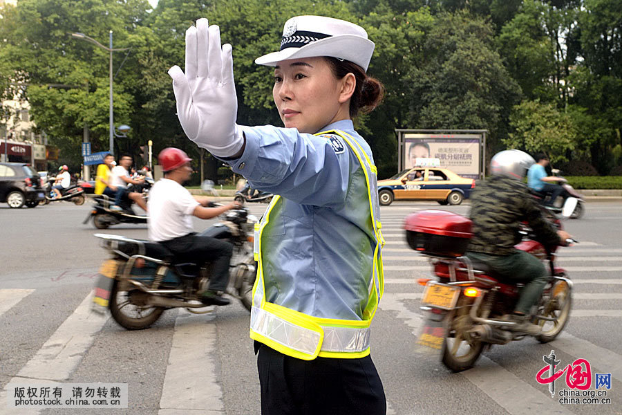  2014年9月19日，一女警在城区烈士街路口执勤，交通“白手套”是交通手势信号，其刚劲、有力、优美、潇洒的英姿已定格在人们心里，成为一道亮丽的风景，成为交警的一个代言词。中国网图片库 陈自德摄