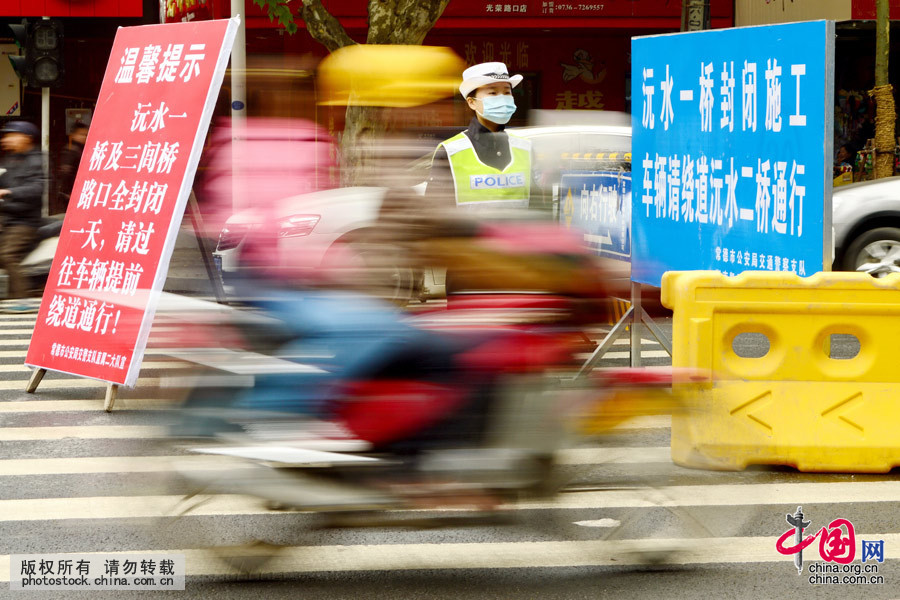 2013年11月26日，一女警在車流中執(zhí)勤。你伴隨著建設中的城市成長，車流與你擦肩而過，在每一個朝陽初升的早晨，或日暮西下的黃昏，車流沿著你的指引駛向通往一路平安的高速。中國網(wǎng)圖片庫 陳自德攝 