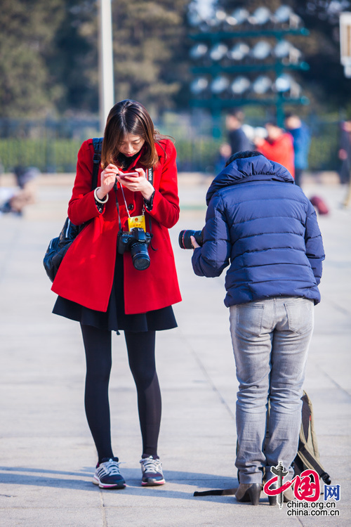 2015年3月5日，第十二屆全國人大第三次會議開幕會，一位紅衣女記者在入場前做最後的準備。中國網 鄭亮 攝