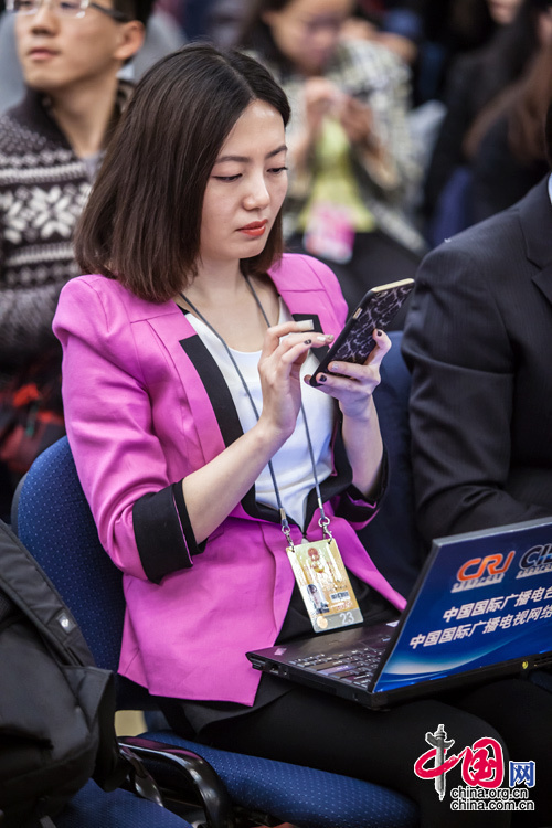 2015年3月8日，外長記者見面會，一位身穿玫紅小西裝的女記者在大會前做準備。中國網 鄭亮 攝