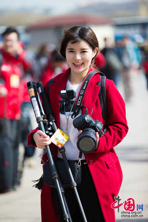 2016年兩會，人民大會大堂前，一位笑容燦爛的紅衣女記者正步入大會堂。中國網 鄭亮 攝