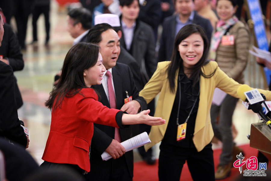 2013兩會，一位著紅色小西裝的女記者為“請”部長也是“蠻拼的”。中國網 楊佳 攝