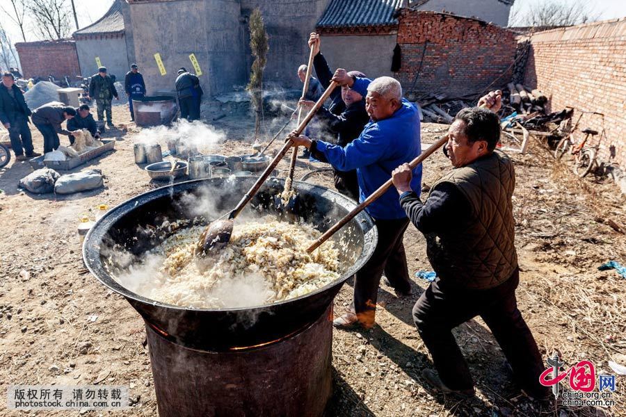2016年3月10日，河南省安阳县水冶镇阜城附近的白龙潭庙会上，“大锅饭”（汤面条）厨师在炒菜。中国网图片库 王子瑞 摄