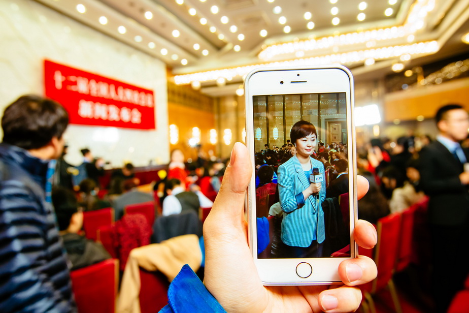 3月4日，一名记者在十二届全国人大四次会议新闻发布会开始前做出镜报道。 新华社记者张铖摄