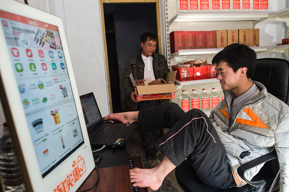 陳茲方（右）在打理他的網店，哥哥陳茲階（左）幫他搬運貨物（3月2日攝）。