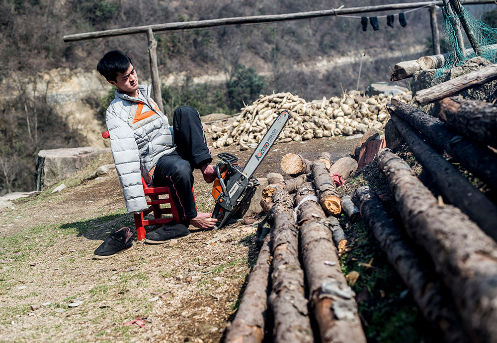 陳茲方在家中用油鋸鋸柴（3月2日攝）。新華社記者 肖藝九 攝