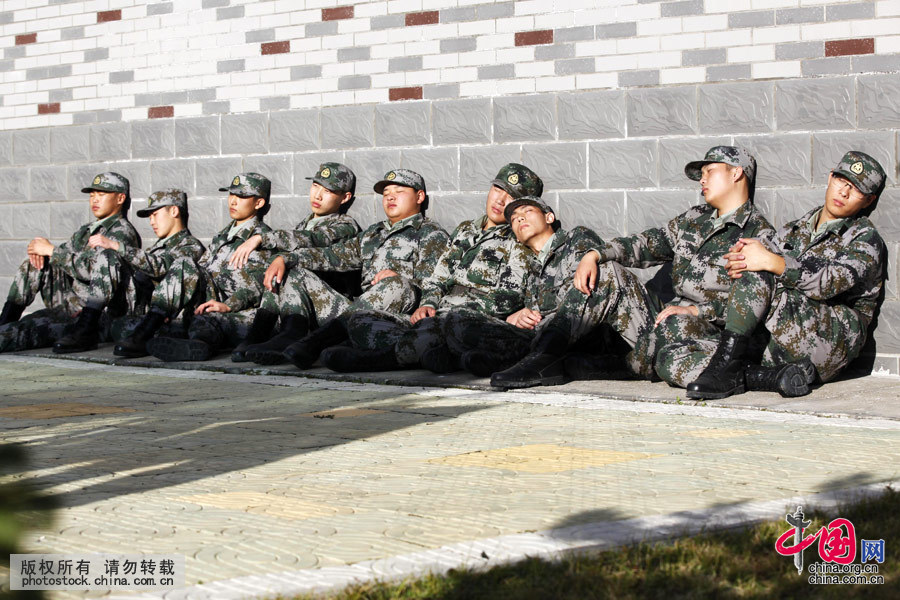  2015年9月29日，黑龍江黑河，剛剛入伍半個月的新戰士，進行了一個多小時的隊列訓練後，利用短暫的10分鐘休息時間，曬著暖陽坐在冰涼的地上睡著了。
