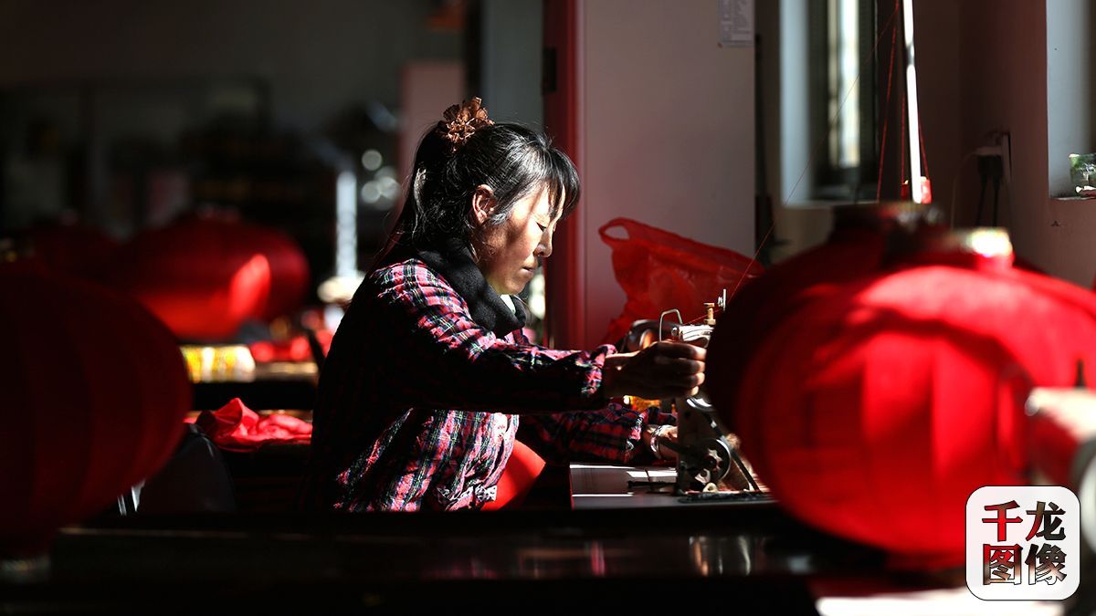 自从灯笼厂开张，潘大姐就在这工作，转眼已有10年之久。每天她都会在窗边的缝纫机上制作灯笼的“外衣”（3月9日摄）。千龙网记者 王悦摄