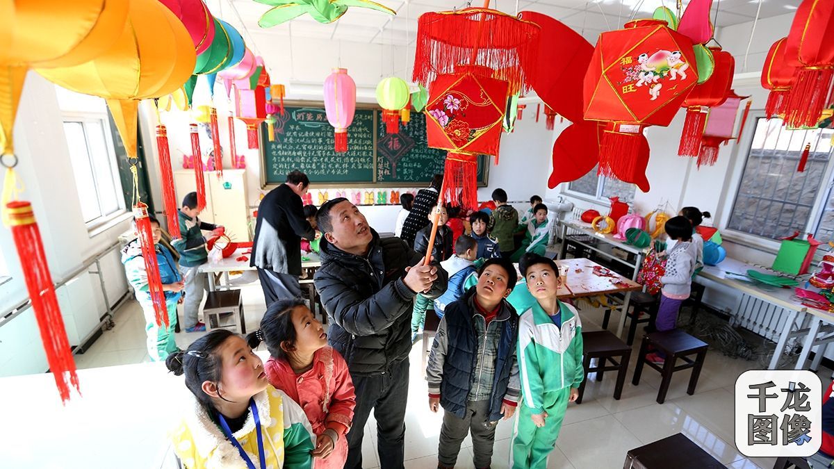 在怀柔区九渡河镇黄花城小学教室内，闫万军带着同学们将刚刚做好的灯笼挂起展示（3月11日摄）。千龙网记者 王悦摄