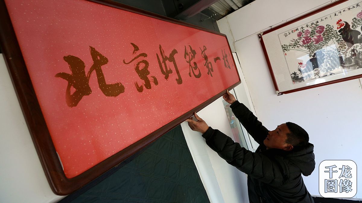 闫万军每天都会将挂在二楼展示大厅内的“北京灯笼第一村”的牌匾擦拭放正（3月9日摄）。千龙网记者 王悦摄