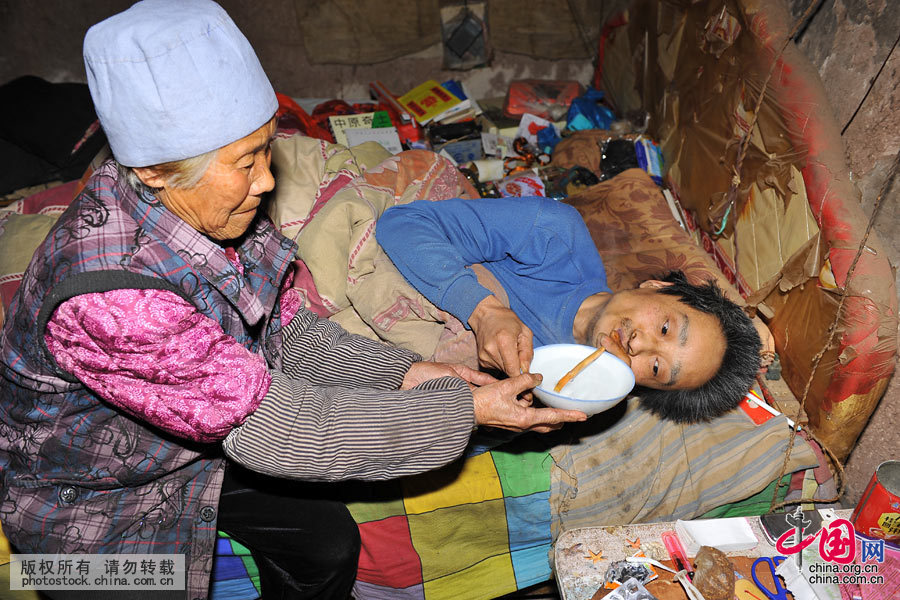 夏培英（左）正在給兒子喝水，由於起不床，只能常年躺在床上，喝水得用一根小水管。中國網圖片庫 劉明照 攝