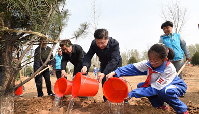 习近平同大家一起给刚栽下的树苗浇水