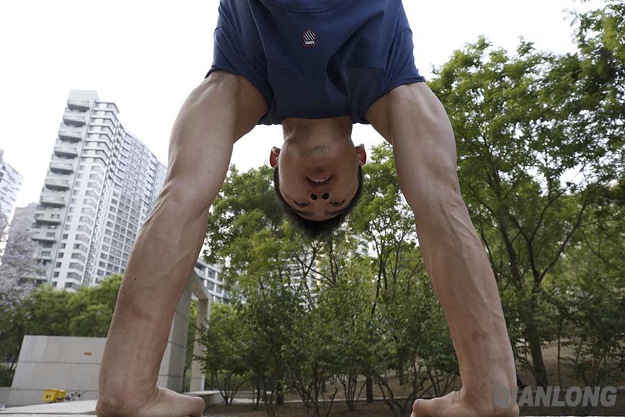 崔健在世贸广场上倒立,向记者展示他手臂上的肌肉.