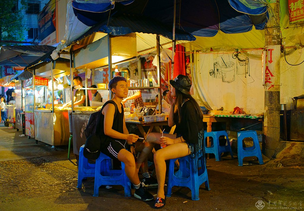 06、一对正在小吃铺前畅聊的姑娘。一个打扮成“假小子”，在这里经常可以看到充满个性化打扮的青年人。（2015.6.12）