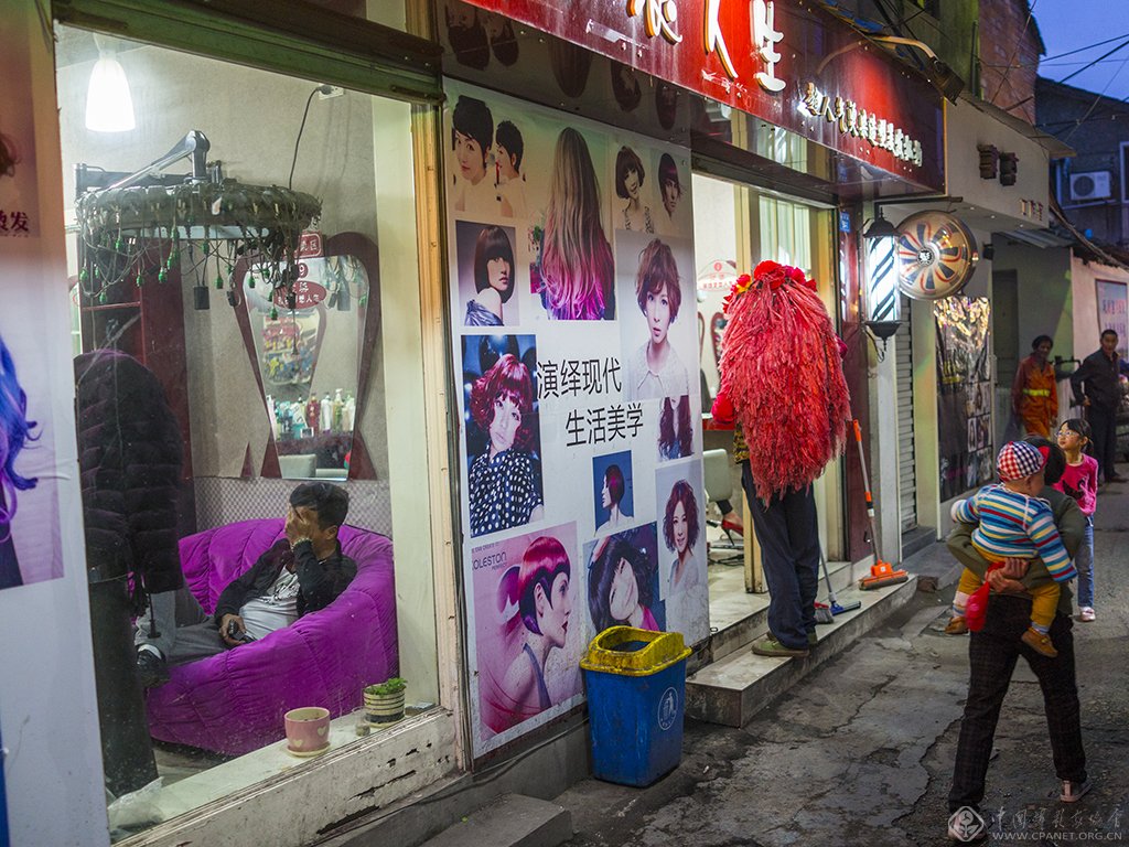 11、美容美发店是这个小巷的特色,一个戴着夸张头饰的乞讨者在美容美发店门口乞讨。(2015.11.30)