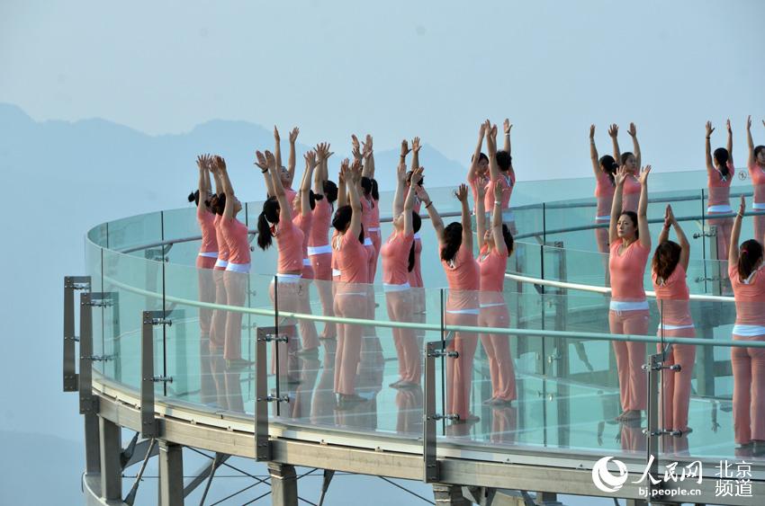 伴着清晨的旭日，瑜珈爱好者在玻璃观景台上练起了瑜珈。人民网尹星云 摄