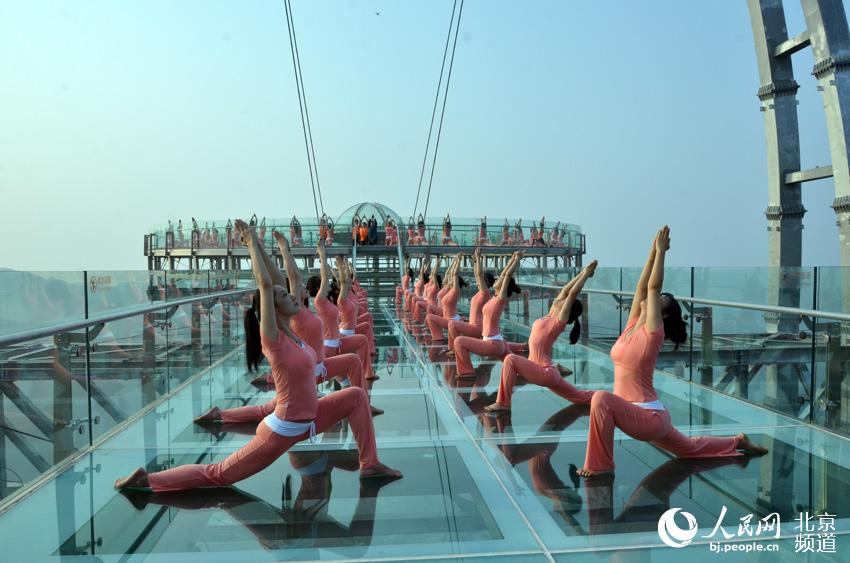 伴着清晨的旭日，瑜珈爱好者在玻璃观景台上练起了瑜珈。人民网尹星云 摄