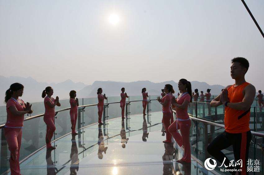 伴著清晨的旭日，瑜珈愛好者在玻璃觀景臺上練起了瑜珈。人民網尹星雲 攝