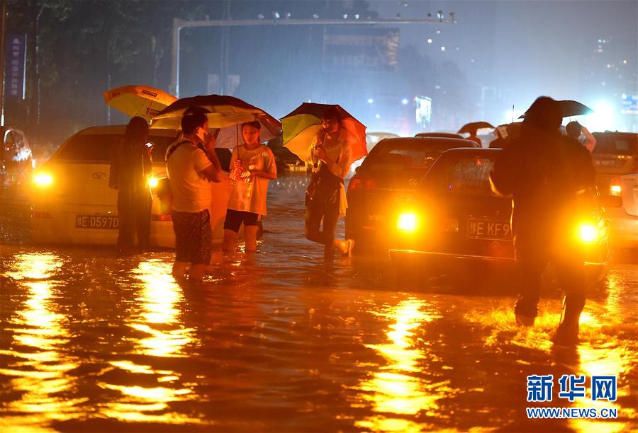 7月19日,汽车和行人在河南安阳市一段积水道路上