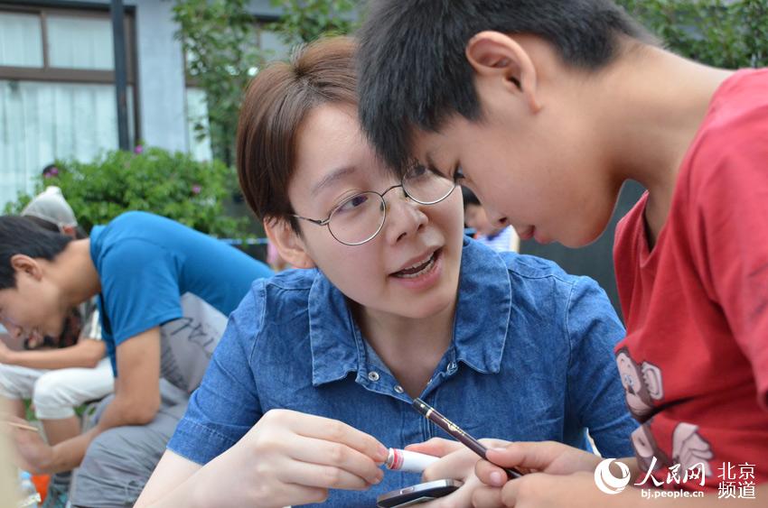 活动现场，大学生志愿者也参与其中，手把手教北京太阳村的孩子画画。人民网尹星云 摄