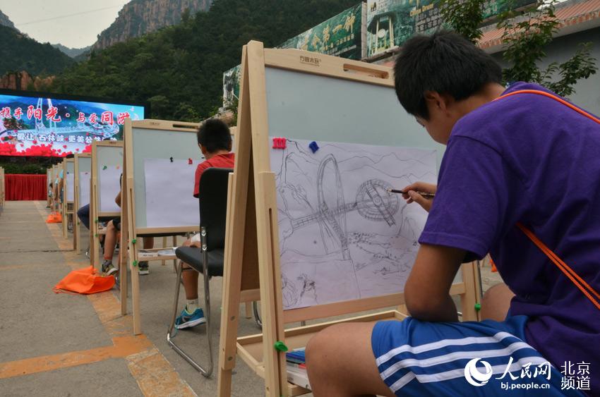 活动现场，一位北京太阳村的孩子们用画笔画出石林峡景区的玻璃观景平台。人民网尹星云 摄