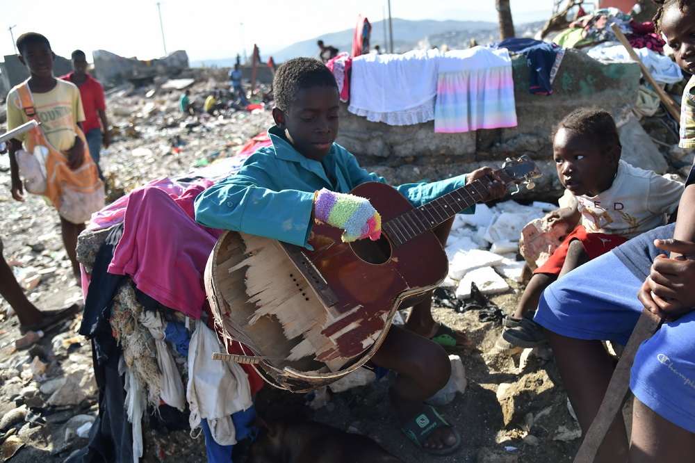 10月8日，在海地熱雷米，一名男孩在廢墟上玩一把破損的吉他。
