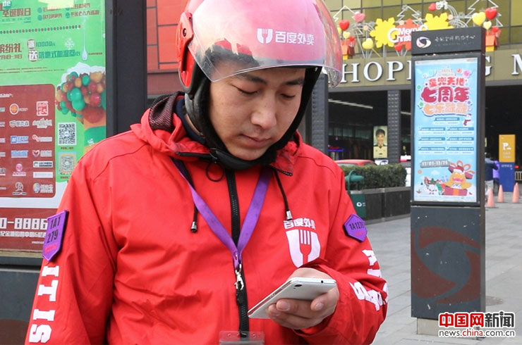 外卖配送员成为了平台和用户之间最直接的“联系”，何磊正在使用手机定位地点。