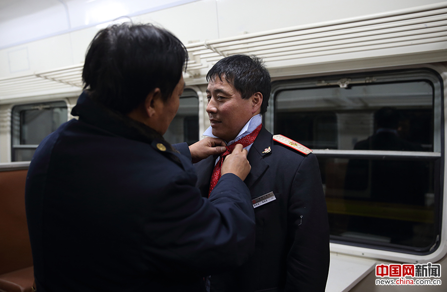 2017年1月12日晚19时，3603次列车乘务员孙井良在同事帮助下系好领带。