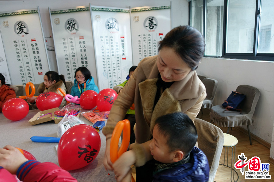 1月23日，一位小朋友的妈妈协助社工，教孩子制作气球灯笼。（中国网王文晔摄）