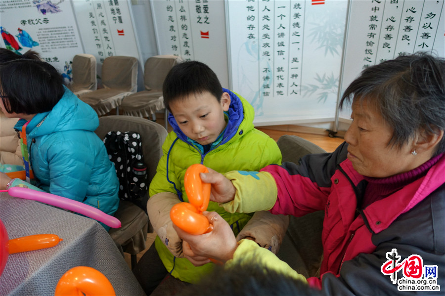 1月23日，一位小朋友的奶奶协助社工，教孩子制作气球灯笼。（中国网王文晔摄）