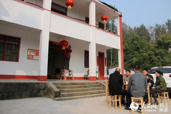 村民胡宗鹏一家和该村“第一书记”张浩在改造后的新房前聊天、晒太阳。（张枥 摄）