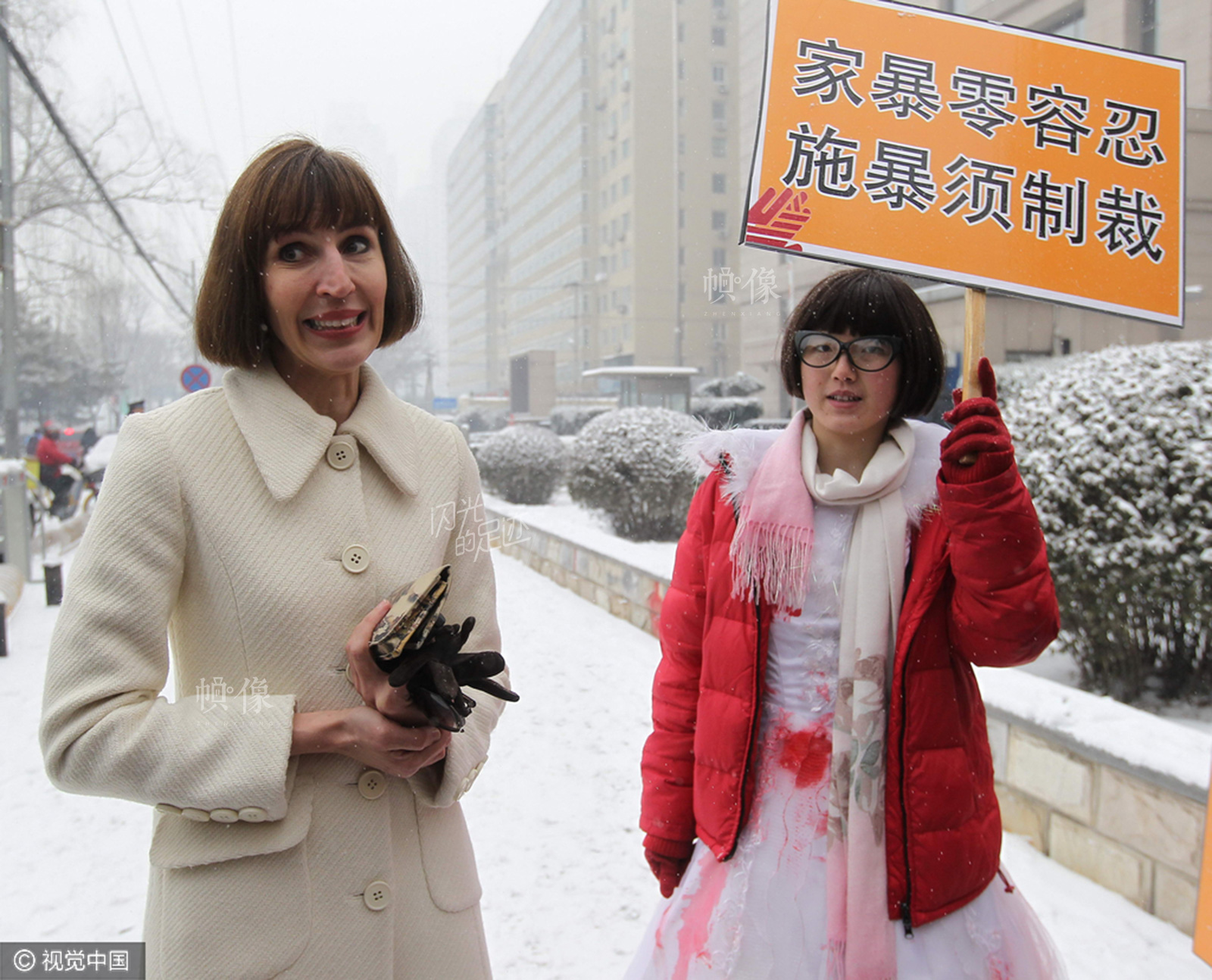 2013年2月3日，北京，疯狂英语创始人李阳离婚案宣判。李阳妻子（Kim Lee）(左)  和举“鄙视”牌的反家暴民众。（视觉中国）