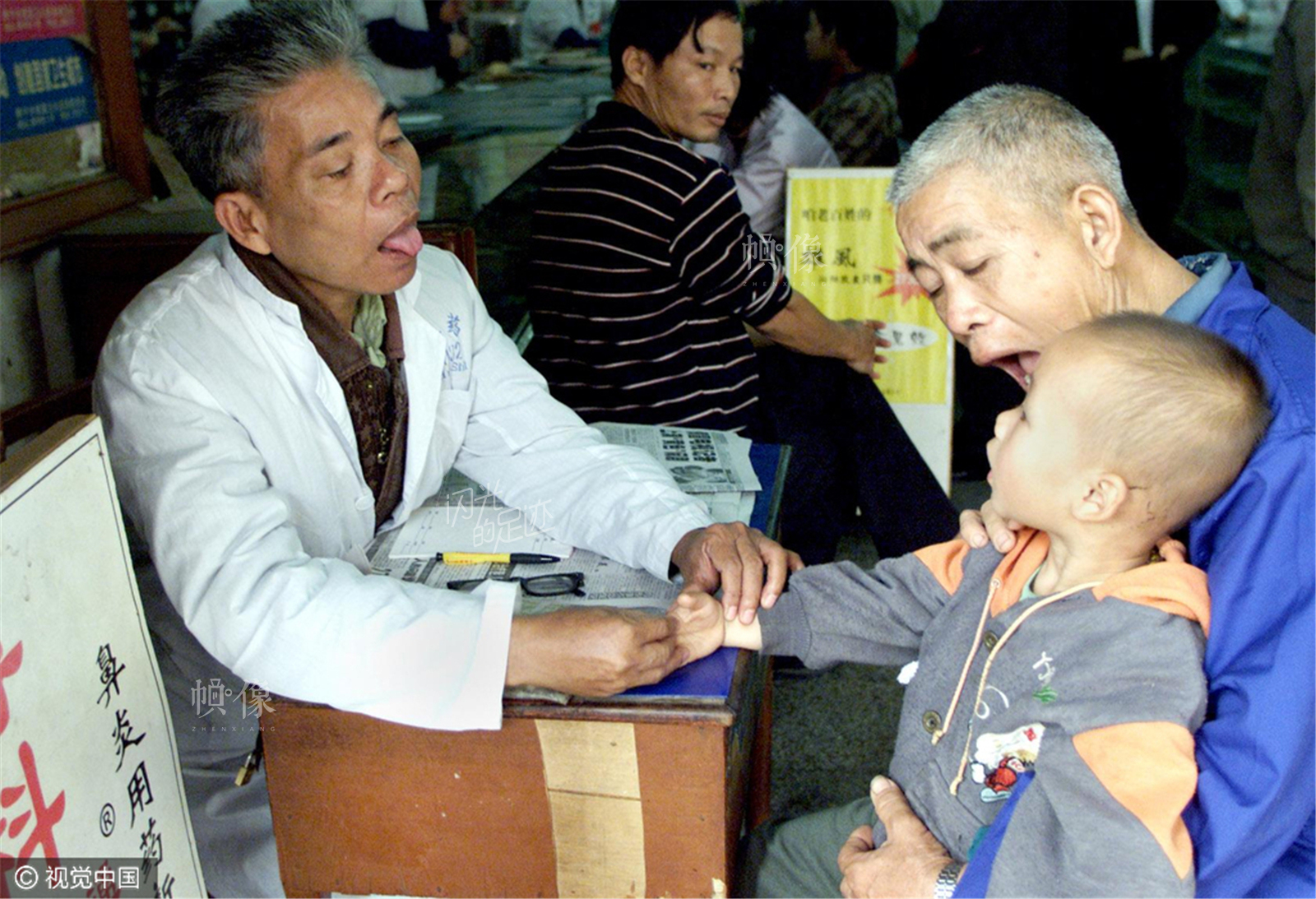 2000年12月28日，广西南宁市解放路一家药店，从乡下赶到城里求医的爷孙俩在请药店聘请来的退休老中医看病。(视觉中国) 