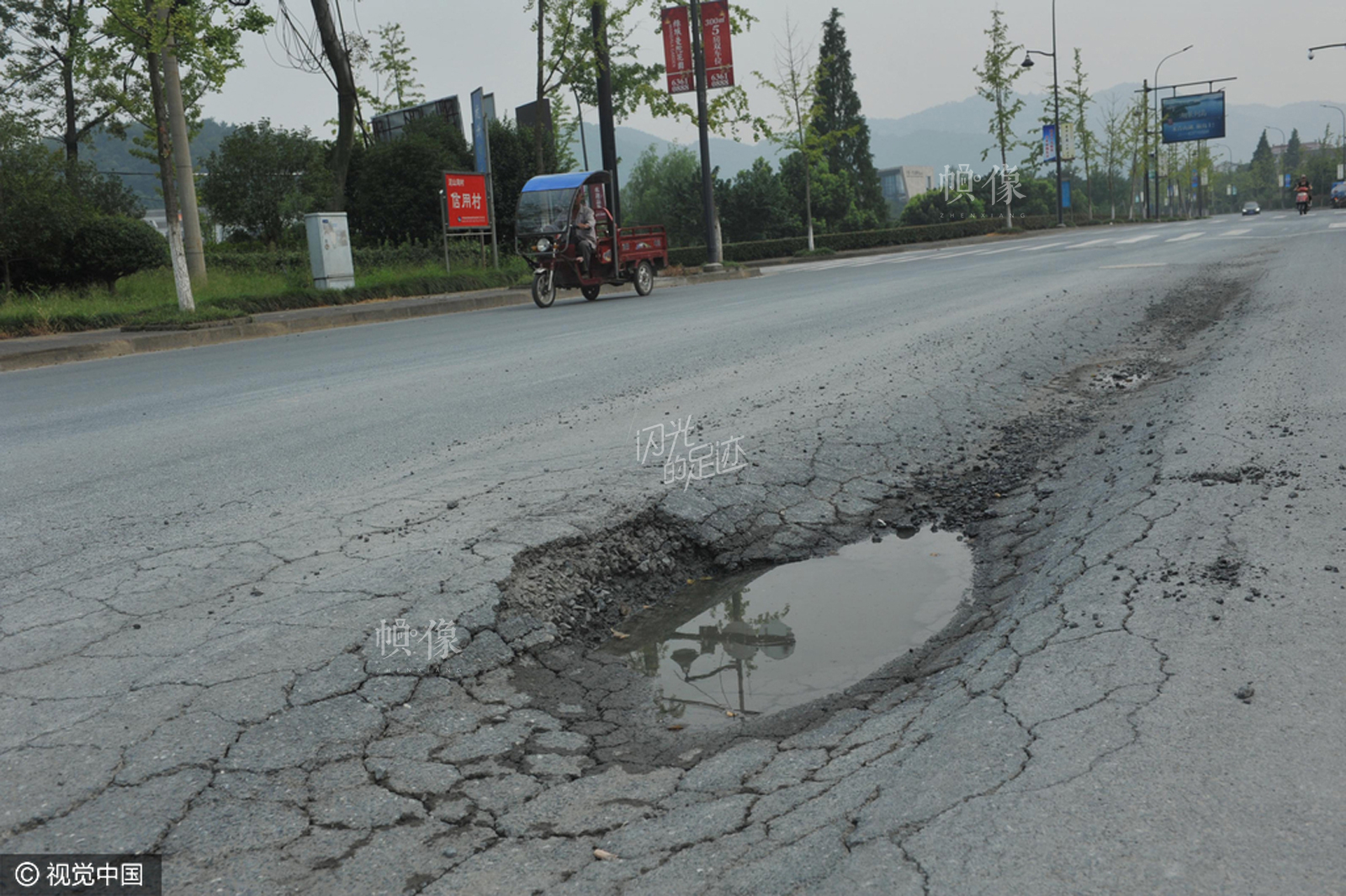 2015年8月30日，浙江省临安市圣元路上，一辆汽车从公路一侧的凹陷路面上驶过。据了解，出现路面凹陷的原因是周边常有超载工程车通过此地。视觉中国