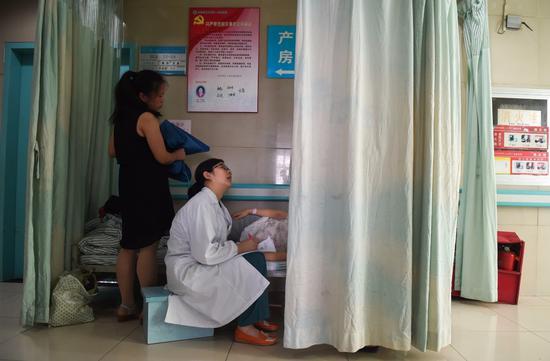 安徽医科大学第一附属医院产科病房内，程桂林医生（左二）向一位加床的产妇询问产前情况（2016年6月29日摄）。新华社记者 郭晨 摄